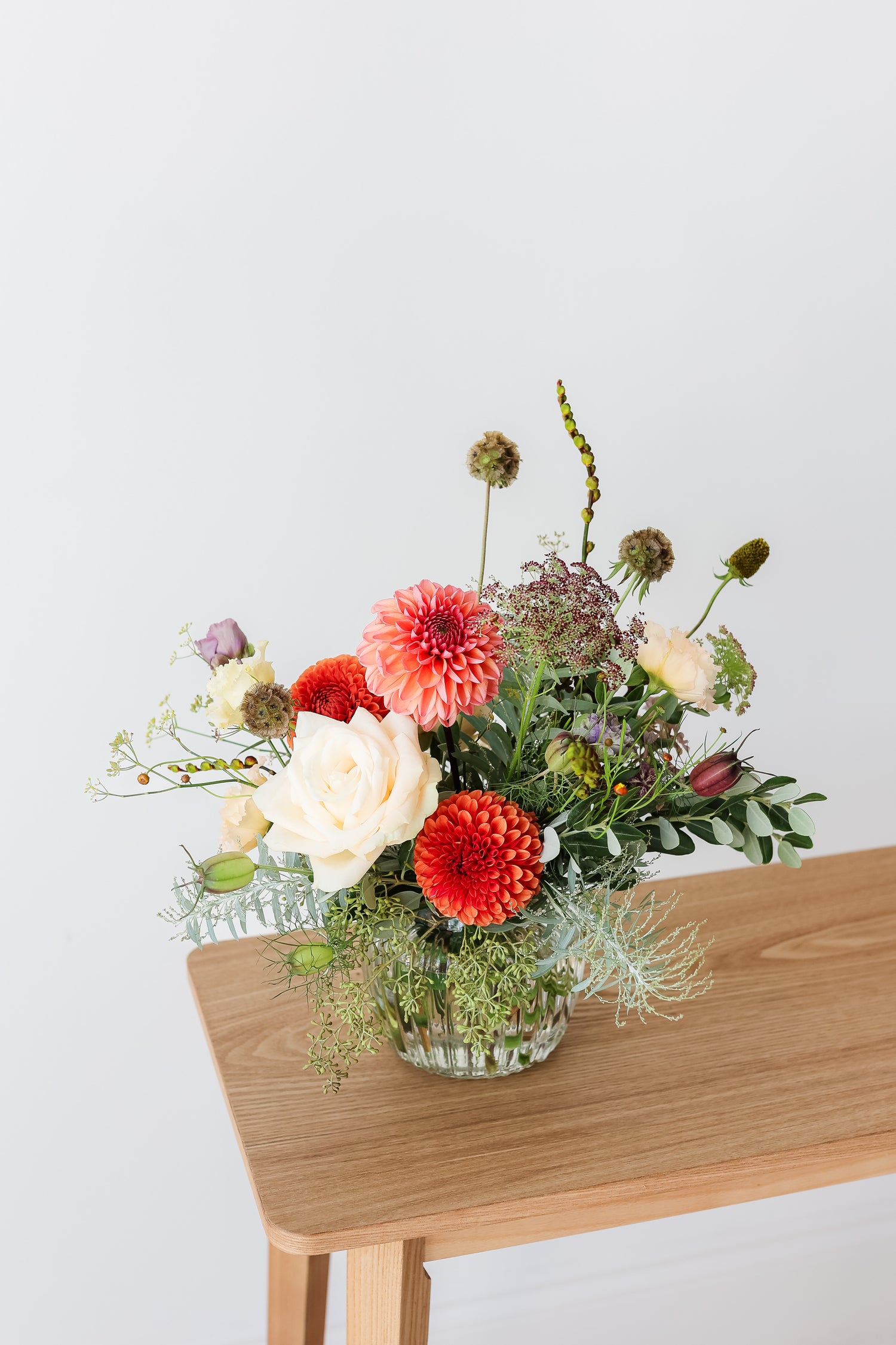 A hand tied bouquet of flowers in a ribbed glass vase
