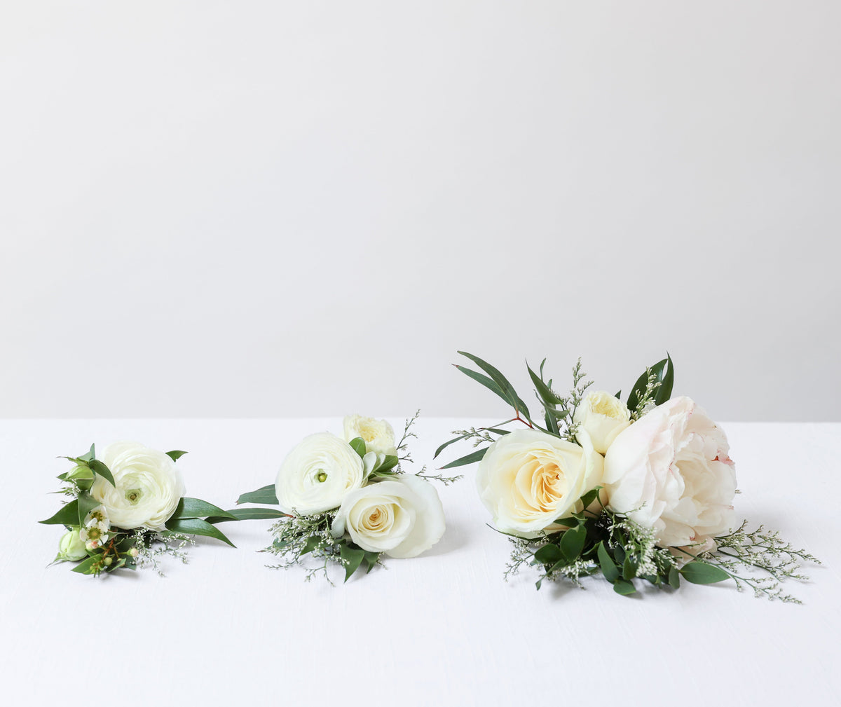 Three small floral bouquets for cakes shown on a white surface with a light gray background