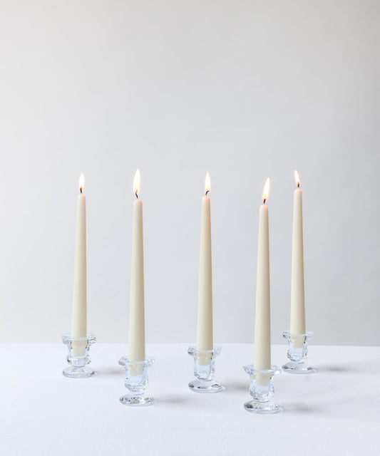 White candles in glass holders on a light gray background